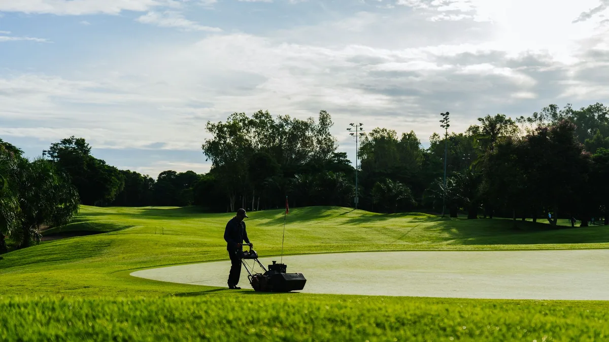 A landscaper mowing a healthy green lawn
